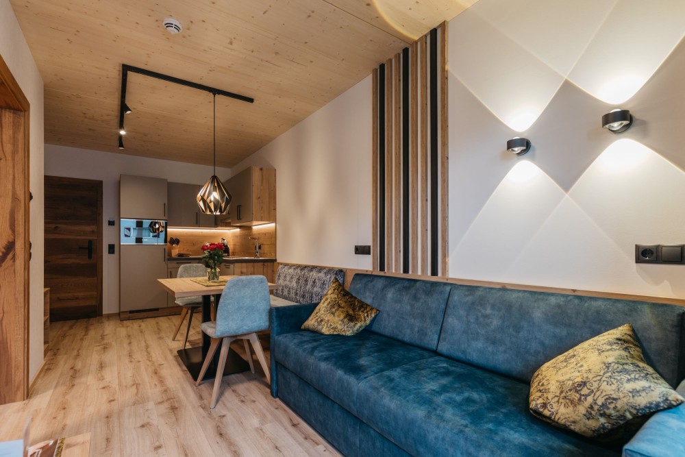 Gemütliches Hotelzimmer mit Sofa, blauen Kissen und Holzwänden im Alpinhotel Berghaus im Zillertal.