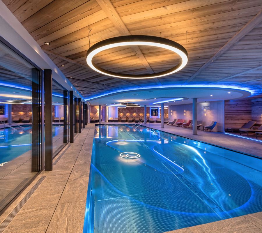 Panoramapool mit Holzdecke, moderner Beleuchtung und großen Fenstern im Alpin Spa des Alpinhotels Berghaus in Tux.
