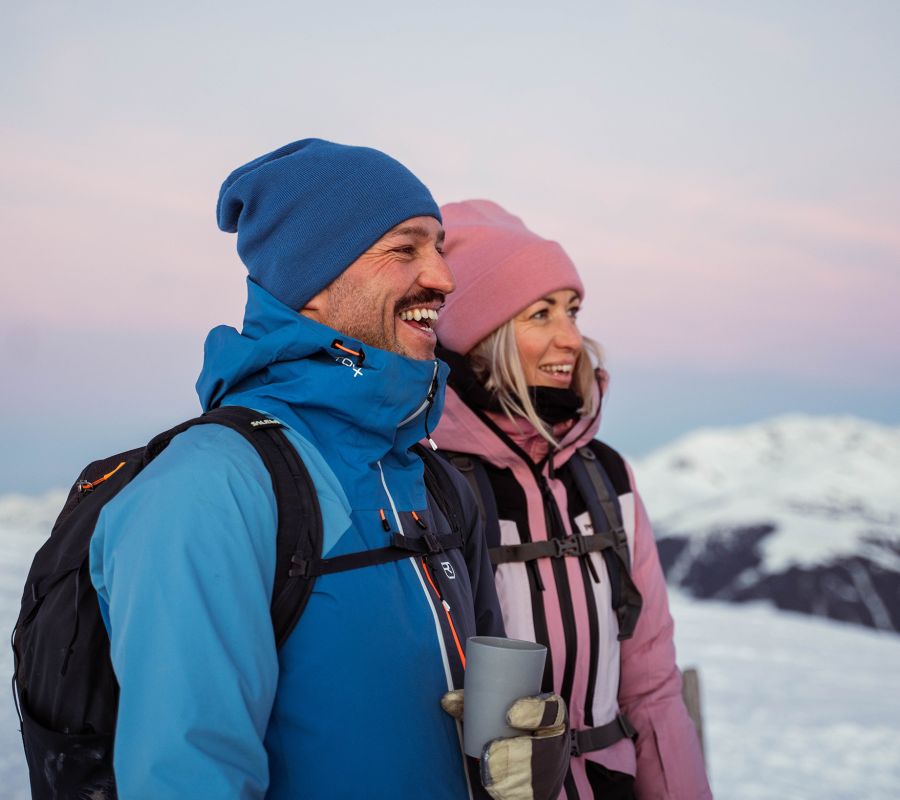 Glückliches Pärchen beim Winterwandern durch verschneite Landschaften im Salzburger Land in einem Wanderhotel in Österreich.