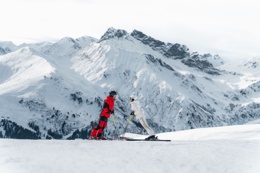 Zwei Skifahrer lehnen sich zueinander vor verschneiten Bergen im Zillertal.