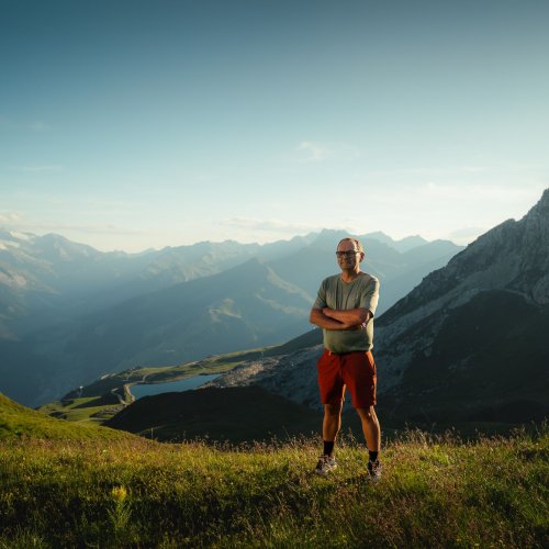Wanderführer Thomas vom Alpinhotel Berghaus steht im Abendlicht auf einer Almwiese vor Bergpanorama im Zillertal.