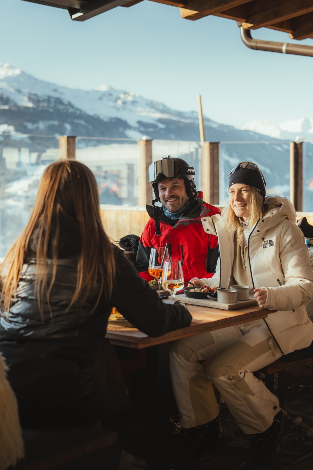 Freunde sitzen in einer gemütlichen Berghütte mit Blick auf die verschneiten Berge im Zillertal.