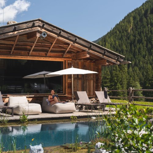 Frau liegt am Badeteich vom Alpinhotel Berghaus beim Urlaub in den Alpen.