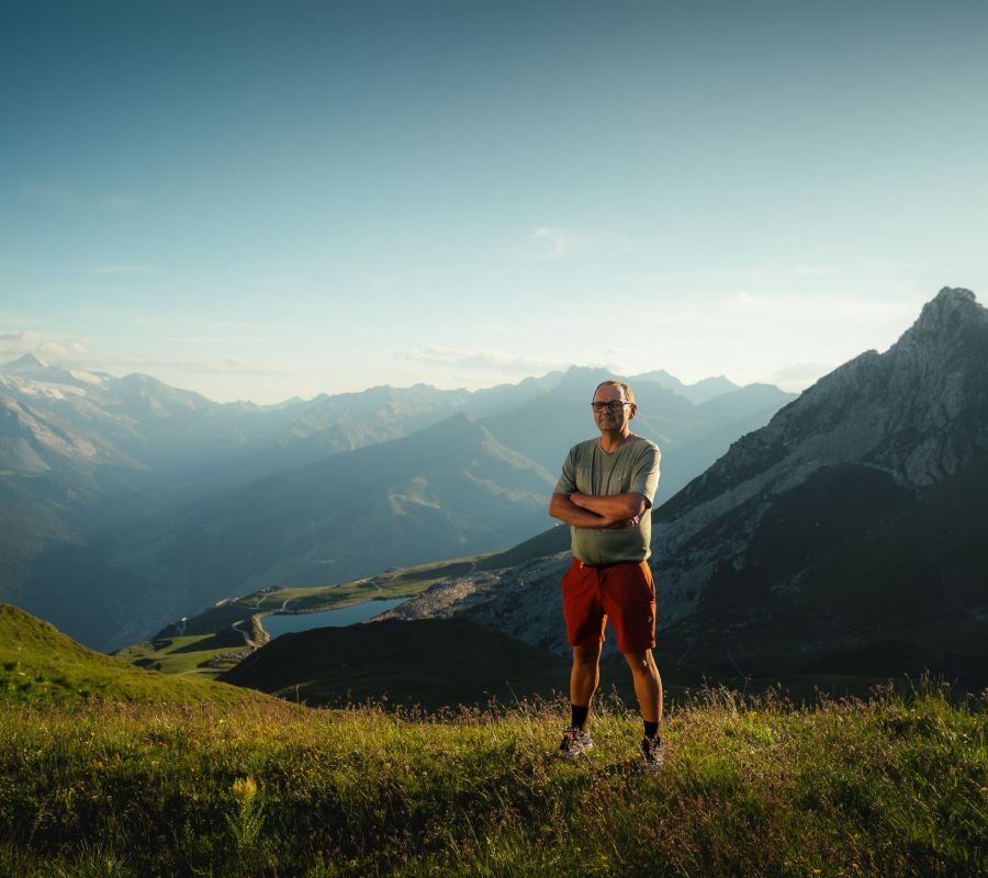 Wanderführer Thomas vom Alpinhotel Berghaus steht im Abendlicht auf einer Almwiese vor Bergpanorama im Zillertal.