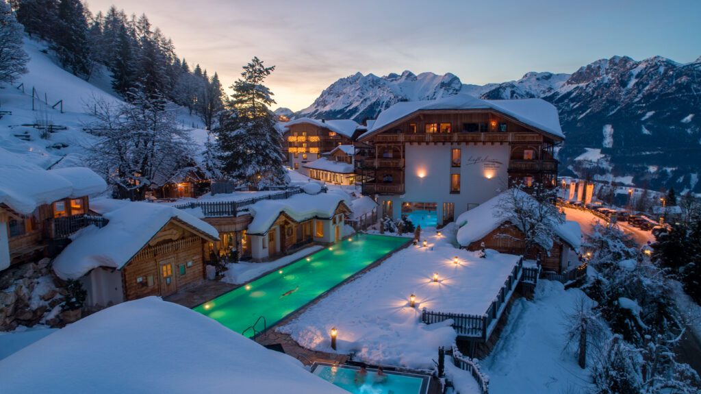 Außenpool vom Hotel Höflehner im Winter, türkisgrün beleuchtet in der Abenddämmerung