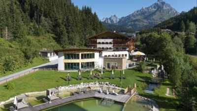 Der sommerliche Naturbadeteich des Wanderhotel Landhotel Alpenhof in Filzmoos in Österreich aus der Vogelperspektive.