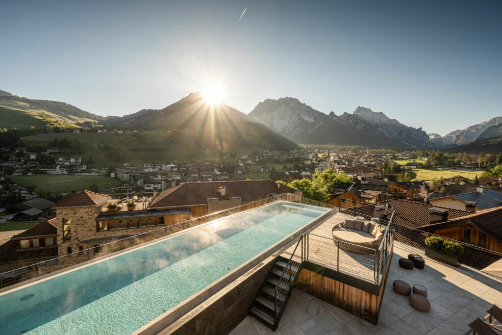 Der Infinity Pool vom Wanderhotel Excelsior Dolomites Life Resorts, der über St. Vigil ragt mit den Dolomiten im Hintergrund