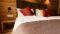 Ein Doppelbett vom Bierhotel Loncium mit Holzwand und roten Kissen(c)-loncium