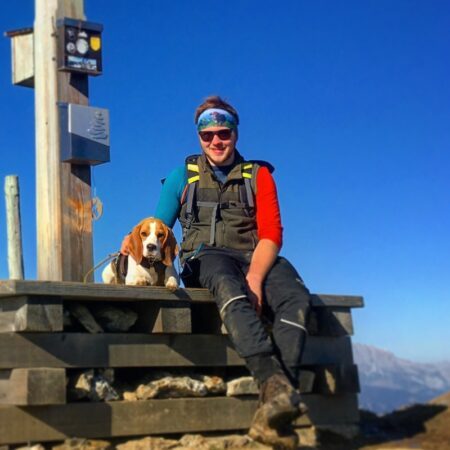 Wanderer sitzt mit Hund auf dem Berggipfel Wanderer sitzt mit Hund auf dem Berggipfel