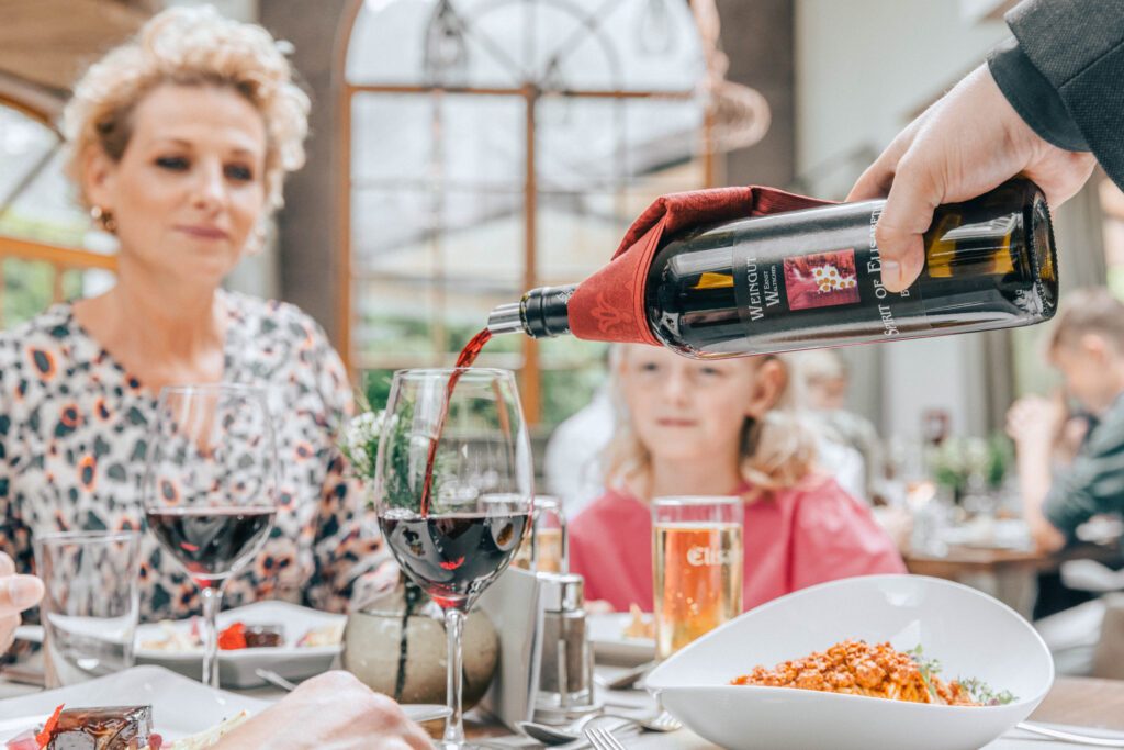 Einer Frau wird Rotwein eingeschenkt