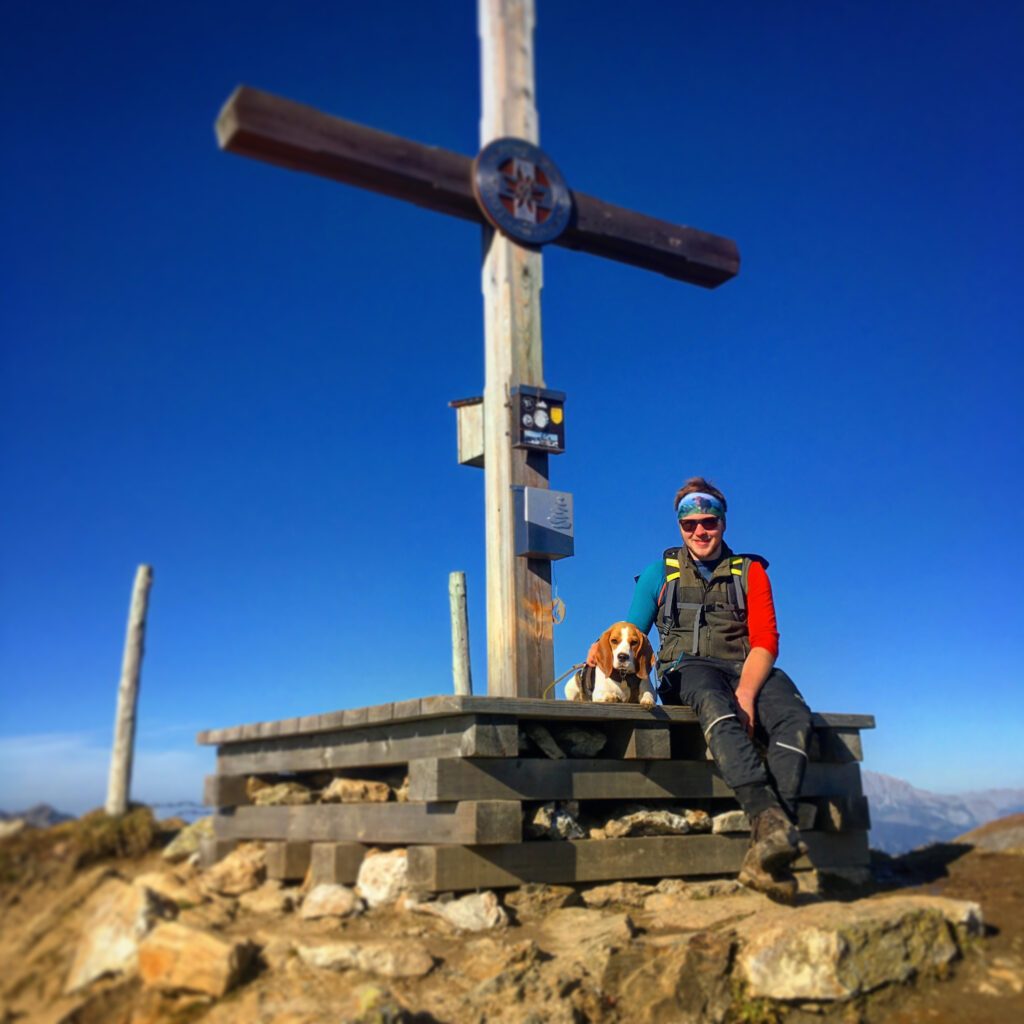 Mann mit Hund am Gipfelkreuz des Penkkopfes