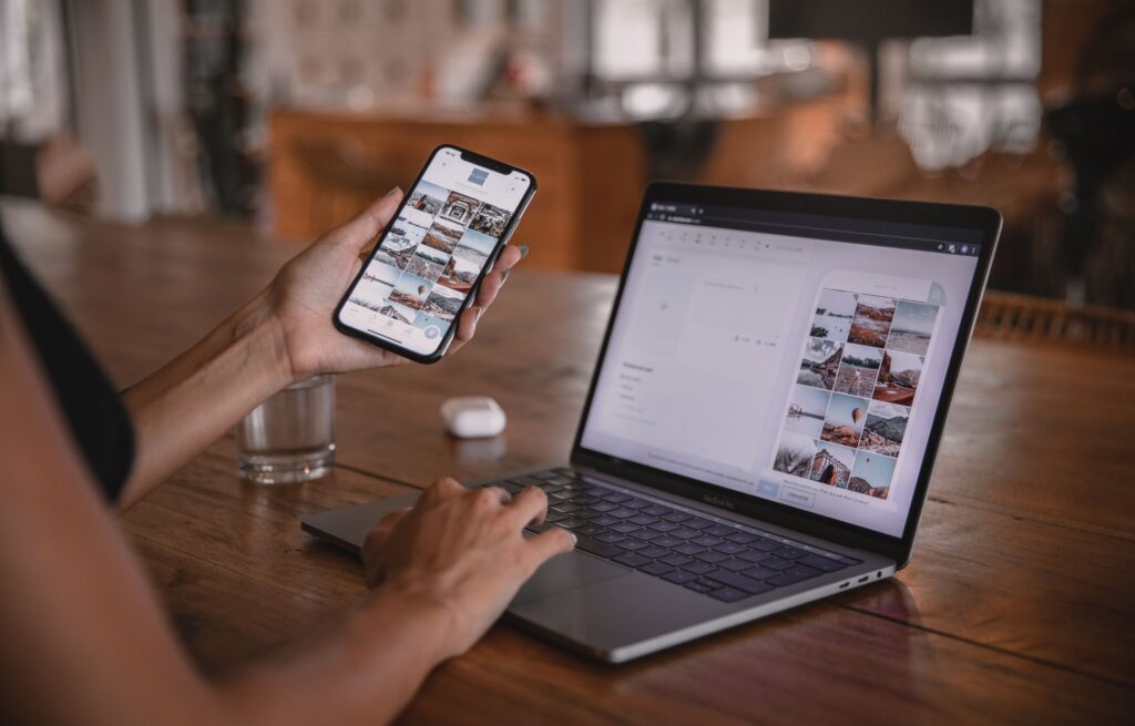 Frau an einem Holztisch mit Laptop und Handy