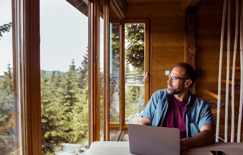 Mann arbeitet am Balkon. Aussicht auf Wald