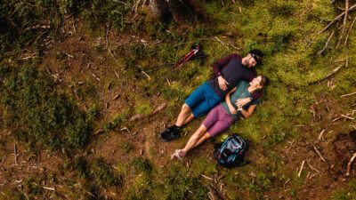 Ein Pärchen liegt auf moosigem Waldboden. Von oben fotografiert.© Wildkogel Arena 