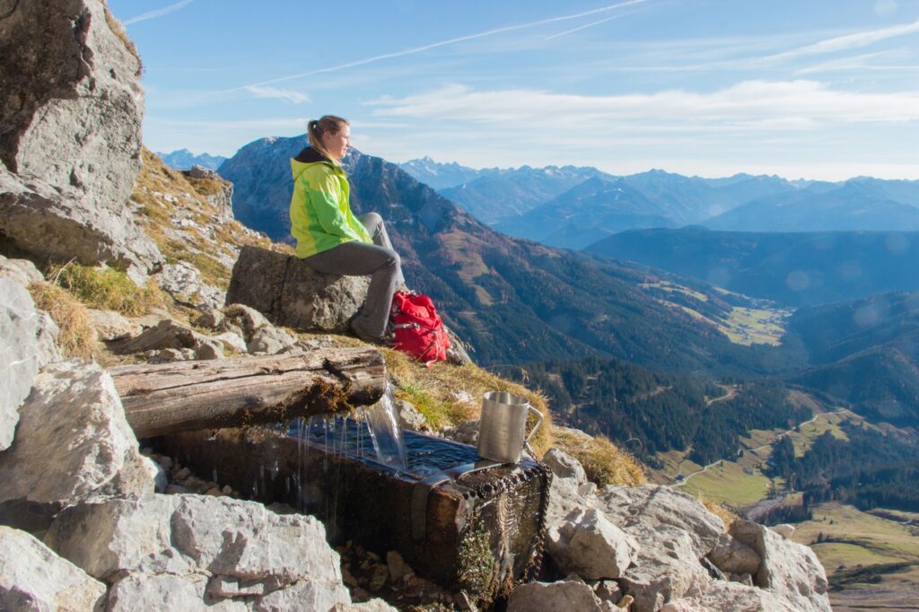 Wanderer sitzt am Berge und schaut in die Ferne