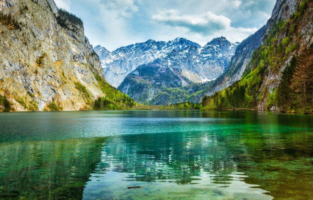 Blaugrüner Bergsee vor einem schneebedeckten Bergmassiv