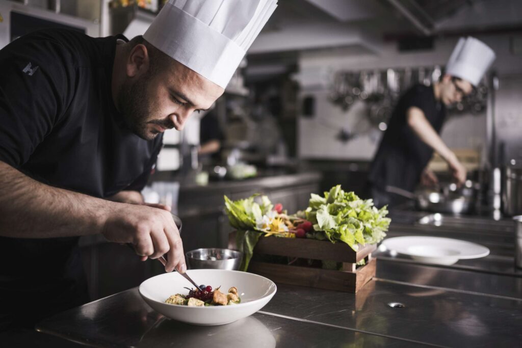 Koch vom Excelsior Dolomites Life Resort perfektioniert ein Gericht in der Hotelküche