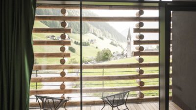 Jaufentalerhof Bild von einem Zimmer mit Blick nach draußen Bett steht vor dem Balkon außen Fassade mit Holz ist ersichtlich(C) Hannes Niederkofler_WEB-3379