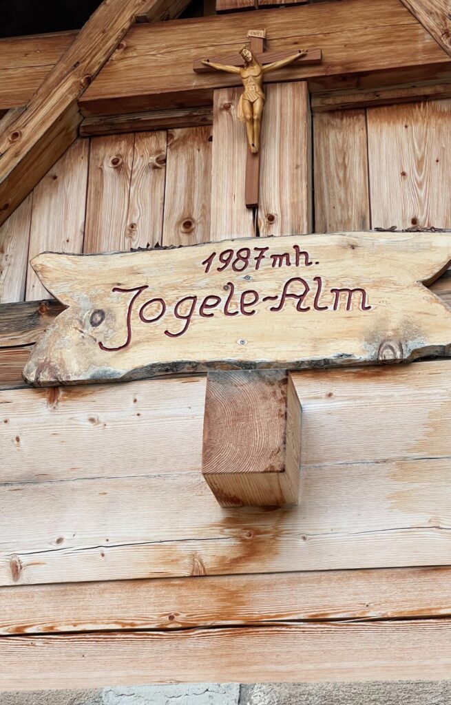 Holzschild auf der Jogelealm-Hütte mit der Inschrift "Jogelealm 1987 mh"