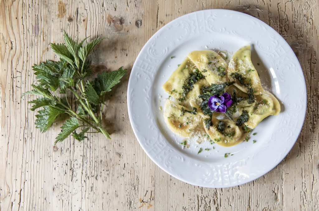 Südtiroler Schlutzkrapfen, hübsch angerichtet mit Kräutern und essbarer Blüte