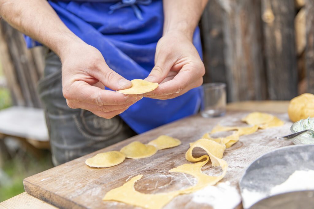 Herstellung von Südtiroler Schlutzkrapfen auf einem bemehlten Holzbrett