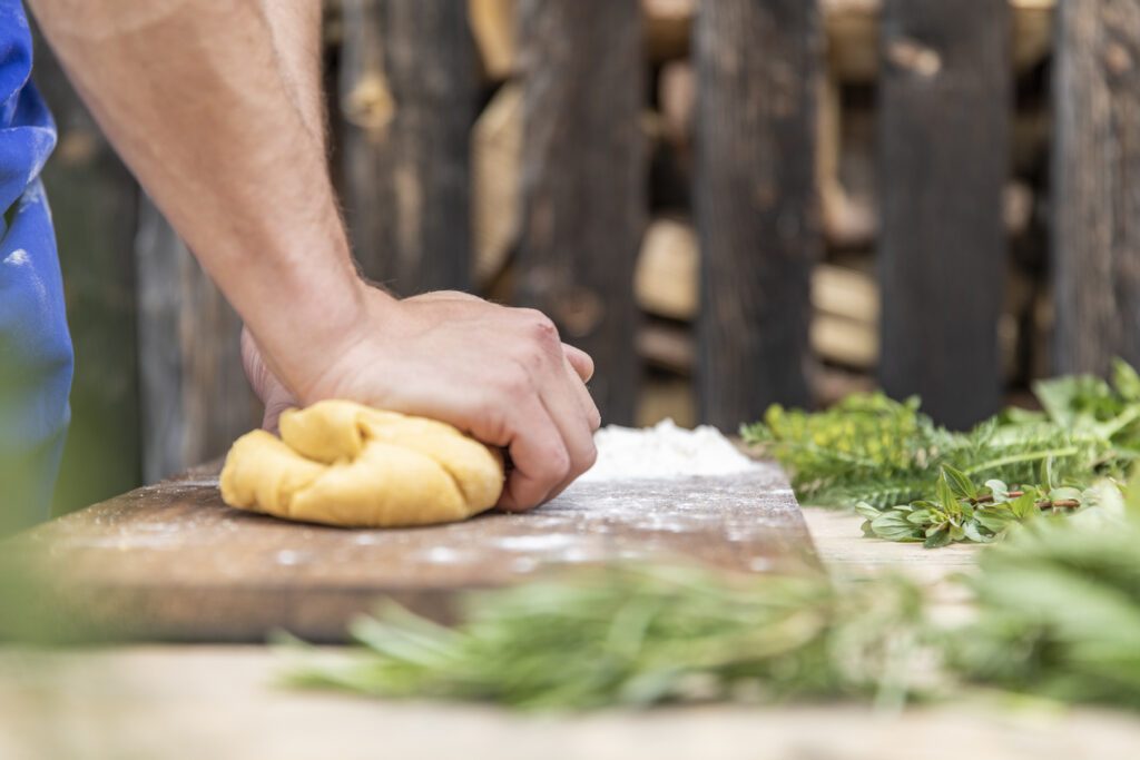 Teig für Südtiroler Schlutzkrapfen wird auf einem Holzbrett geknetet