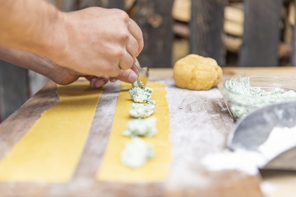 Fülle für Südtiroler Schlutzkrapfen wird mit einem Löffel auf Teig gelegt