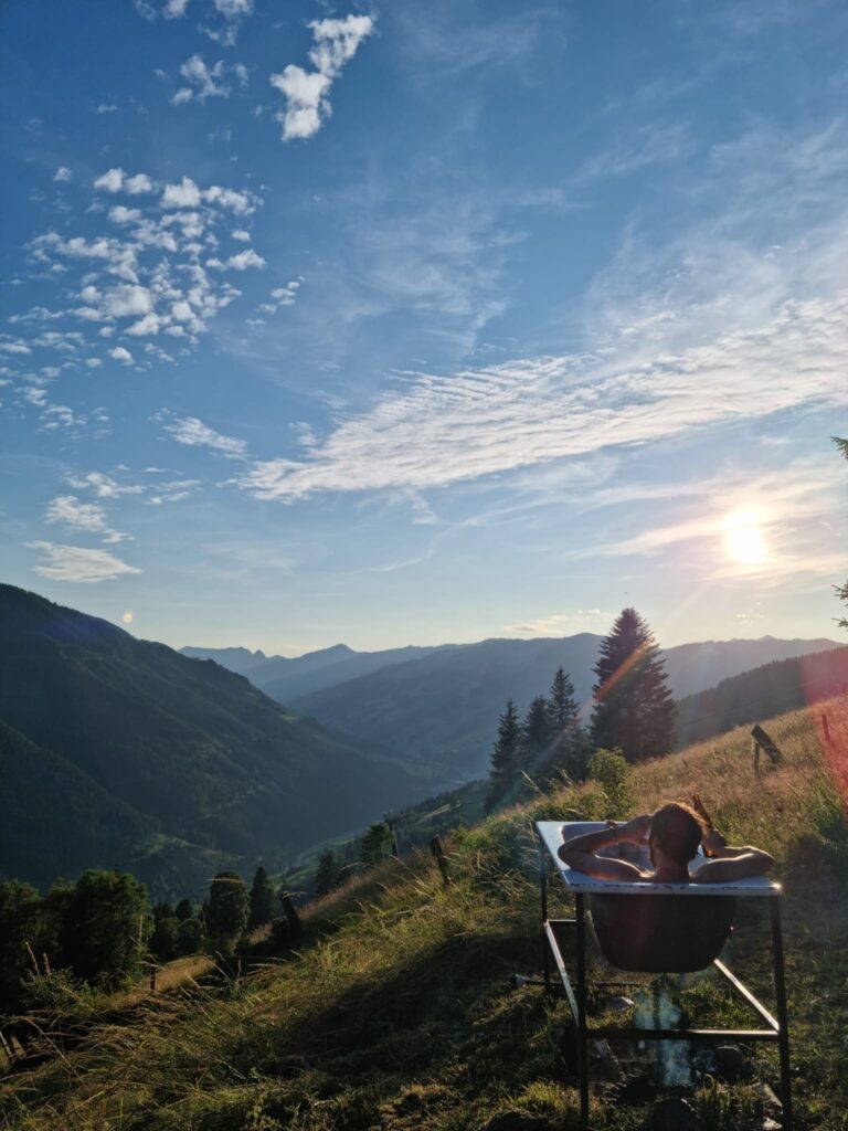 Mann sitzt in einer Badewanne mit Blick über das Tal von Vorderglemm