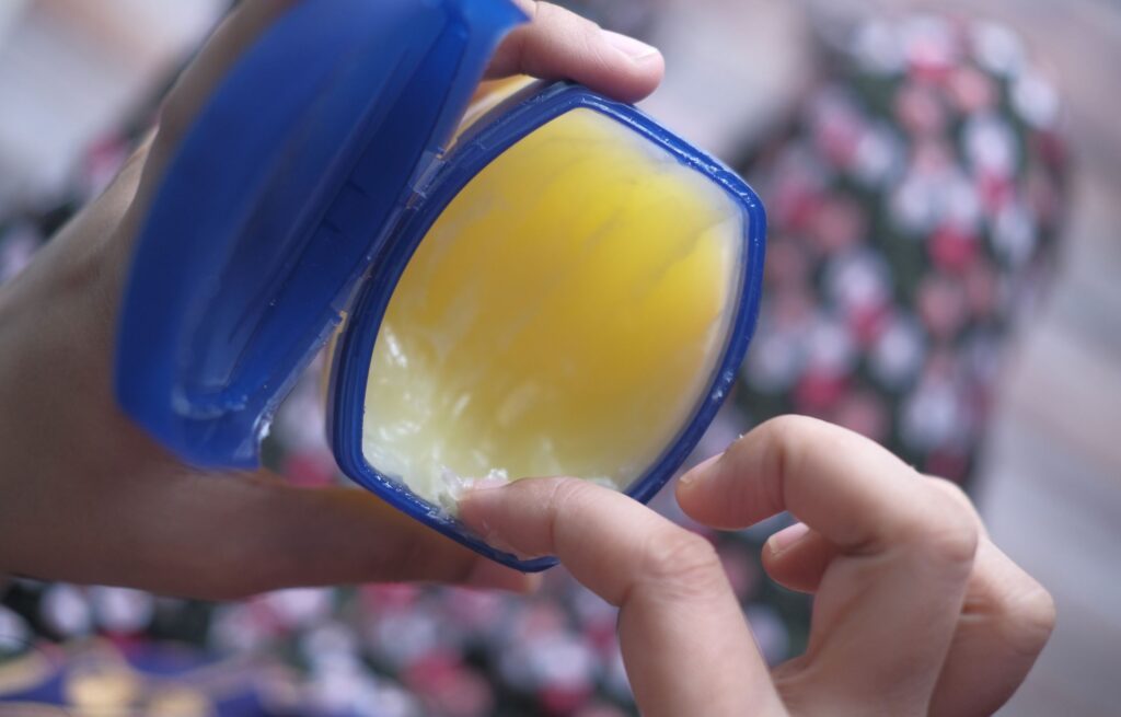 Jemand nimmt aus einem offenen Tiegel Vaseline