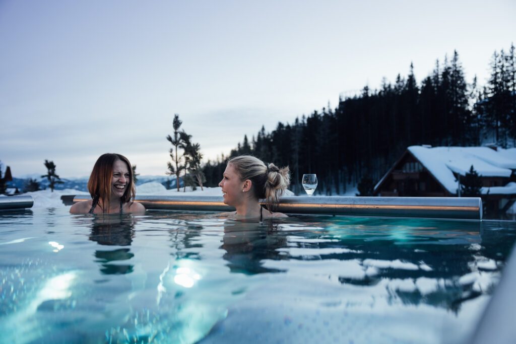 Freundinnen im Außenpool vom Hotel DAS KATSCHBERG mit Winterlandschaft im Hintergrund