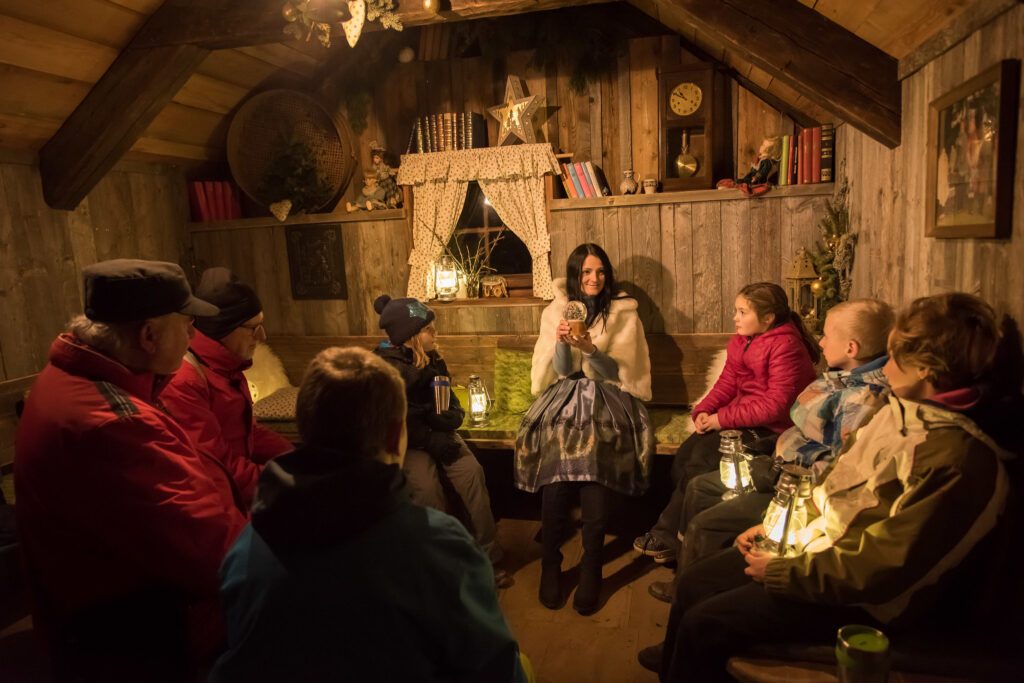 Menschen sitzen gemütlich in einer weihnachtlich geschmückten Hütte am Katschberger Adventweg