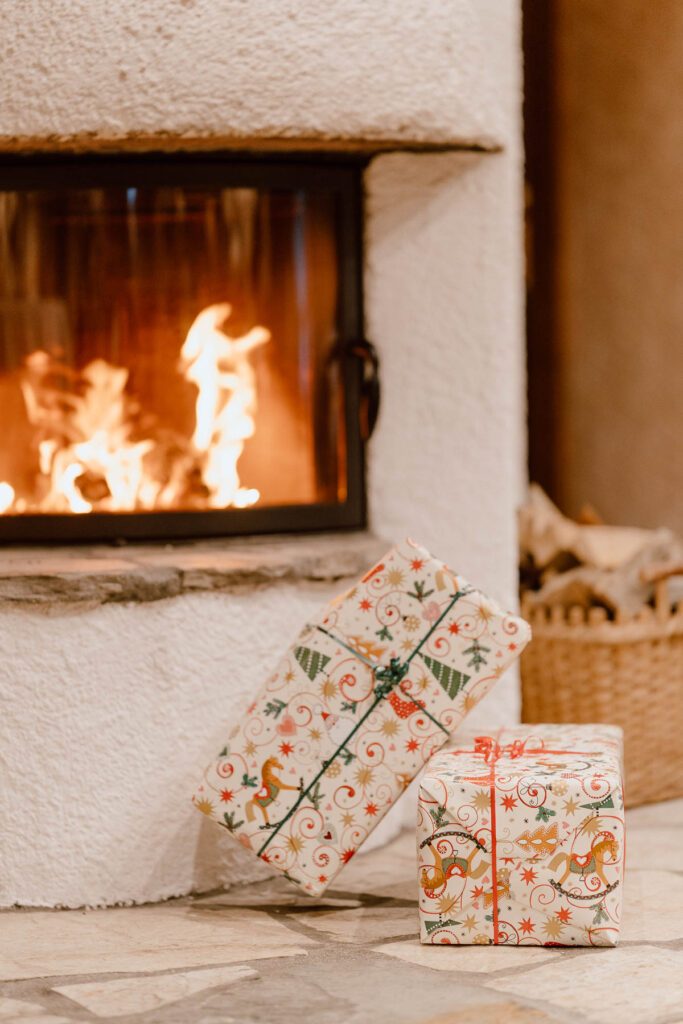 Weihnachtsgeschenke liegen vor dem brennenden Kamin im Wanderhotel Vierbrunnenhof im Südtiroler Antholzertal