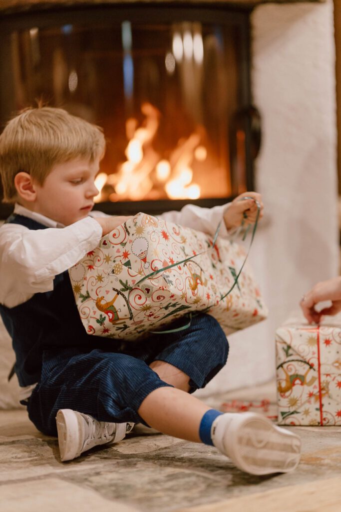 Kind packt Weihnachtsgeschenke aus im Wanderhotel Vierbrunnenhof im Südtiroler Antholzer Tal