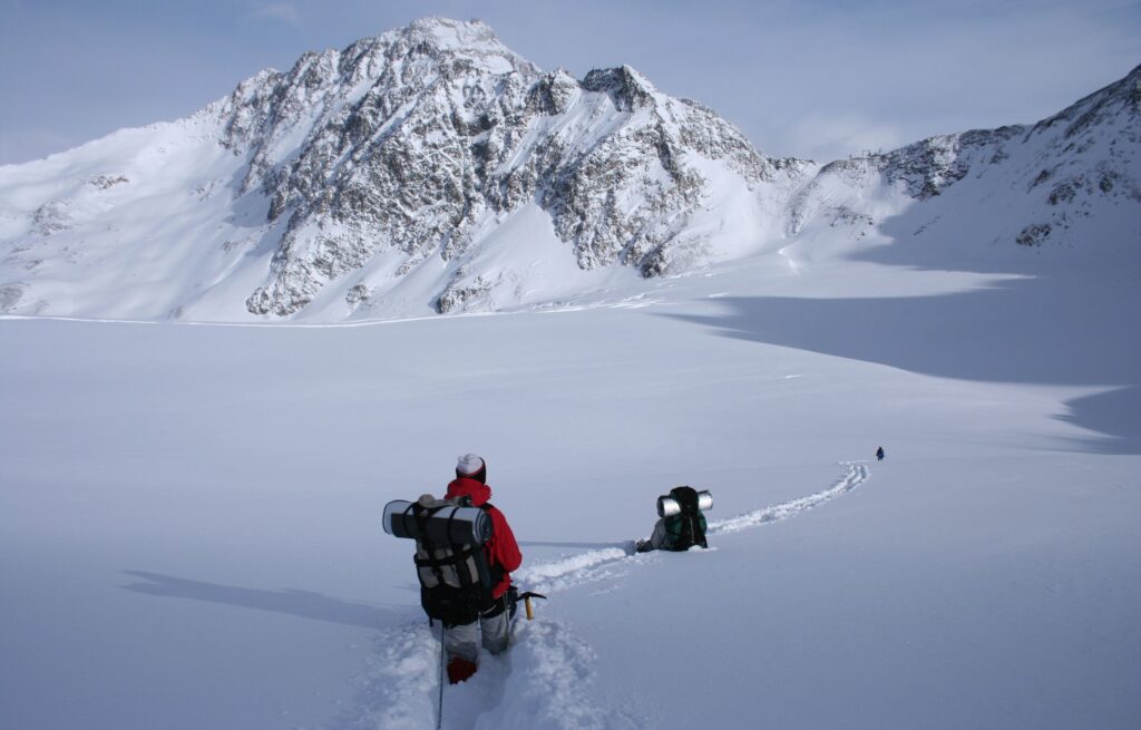 zwei Winterwanderer stapfen hochalpin durch hüfthohen Schnee