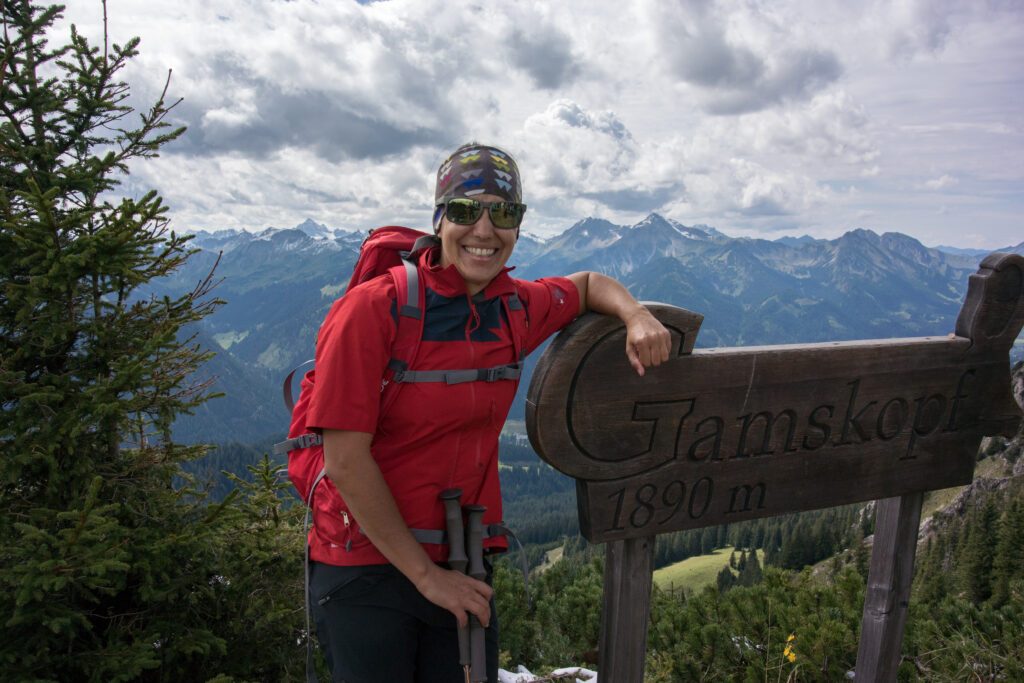 Ramona vom Lumbergerhof stütz sich bei einem Wanderschild ab währen einer Wanderung