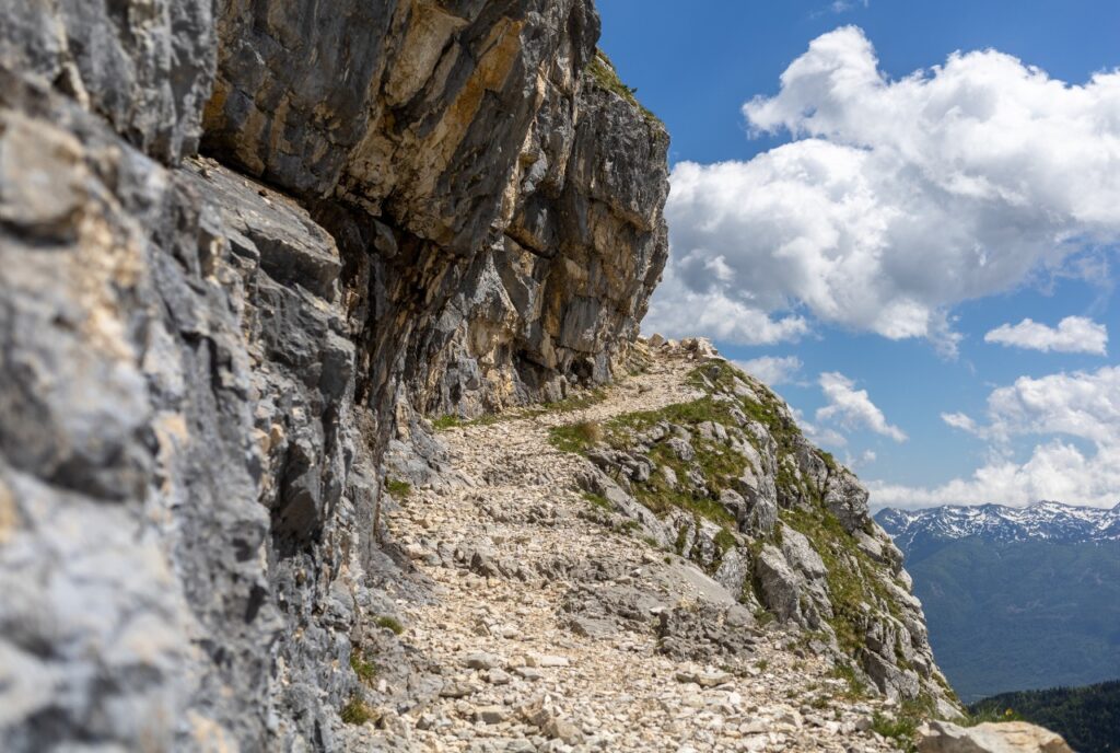Steiniger Wanderweg entlang einer Felswand mit exponierter rechter Seite