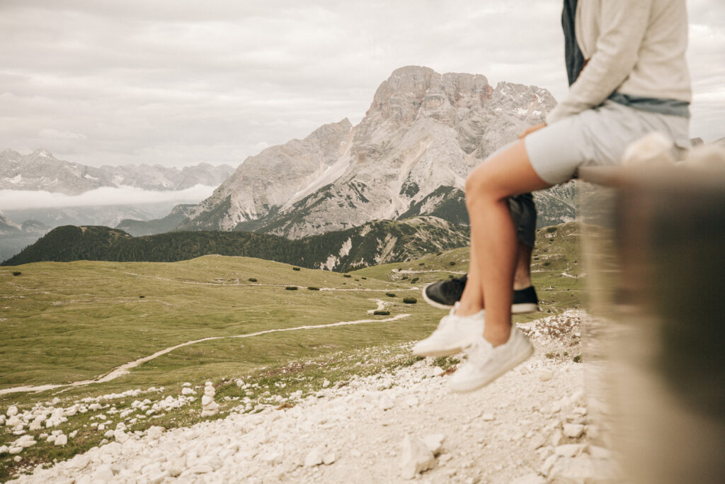 Wanderer sitzen auf einer Bank in den Bergen und lassen die Beine baumeln. Minimalistischer Urlaub in den Alpen